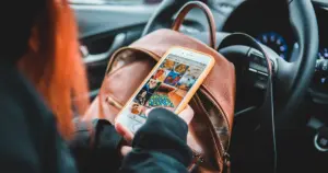 Person browsing social media on smartphone while sitting in car